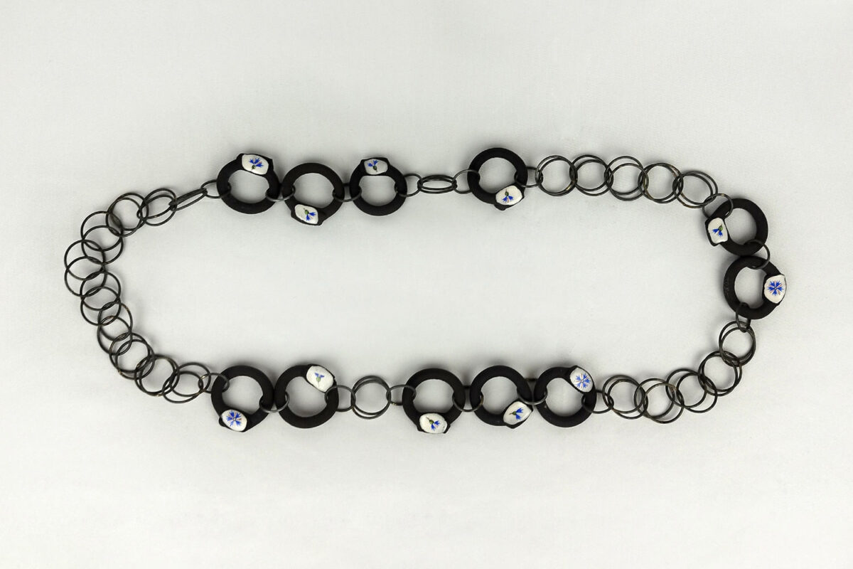 Photo : Centauré enchainé. Collier, 2024, Grès noir, porcelaine émaillée, chromos et acier.