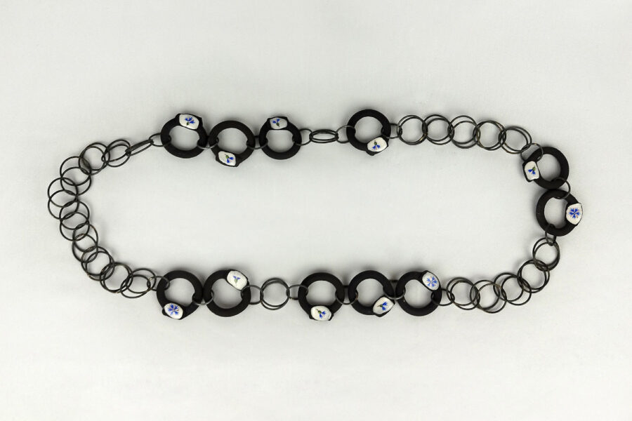Photo : Centauré enchainé. Collier, 2024, Grès noir, porcelaine émaillée, chromos et acier.