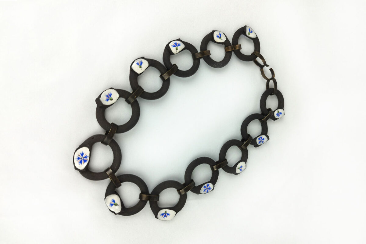 Photo : Centauré bleuet. Collier, 2024, Grès noir, porcelaine émaillée, chromos et laiton noircit.