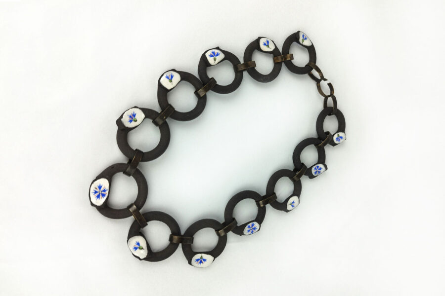 Photo : Centauré bleuet. Collier, 2024, Grès noir, porcelaine émaillée, chromos et laiton noircit.